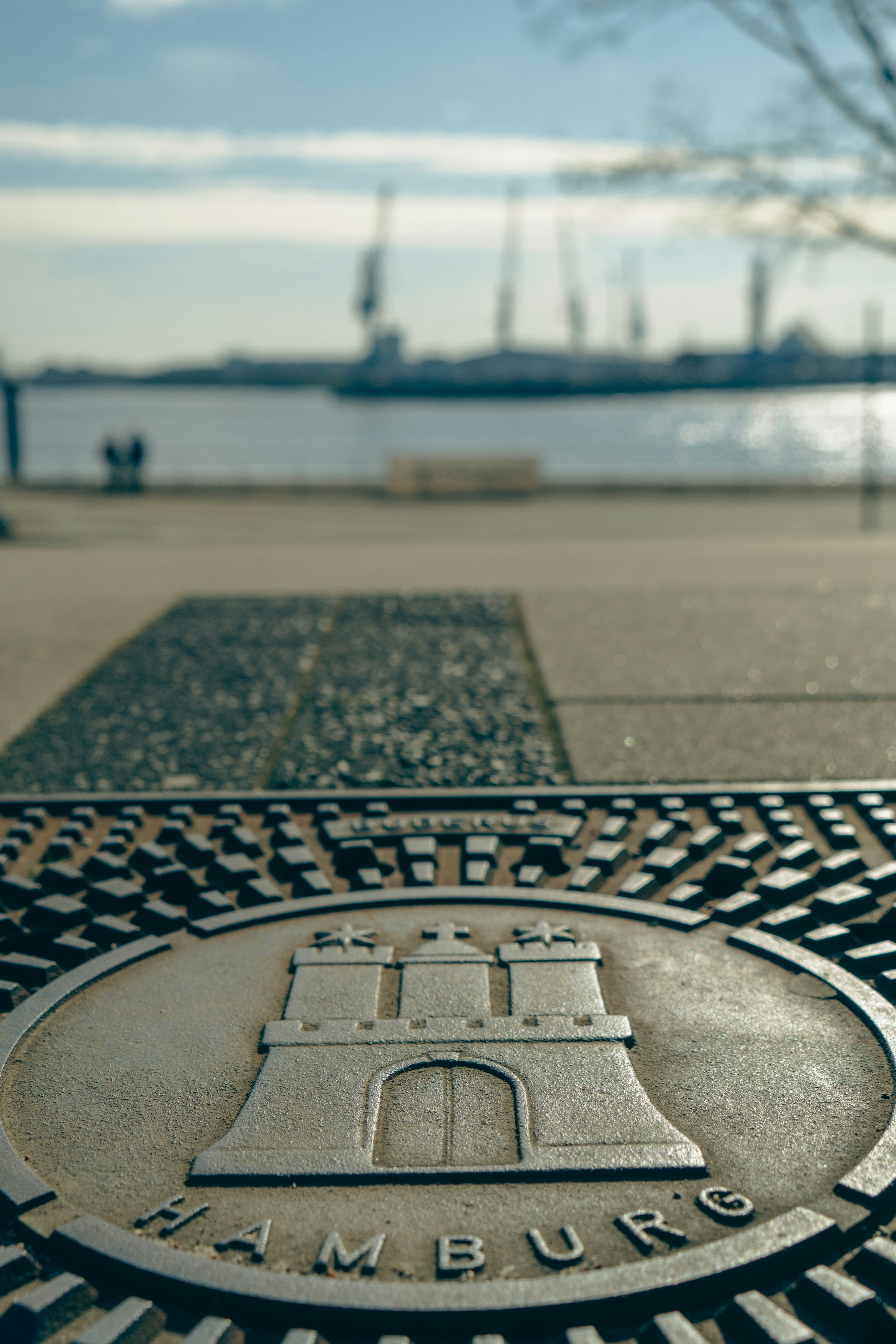 Hamburg coat of arms on metal plaque with blurred harbor.